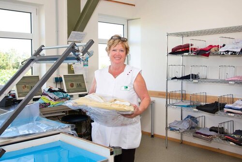 Eine Frau trägt einen Stapel frischer Bügelwäsche