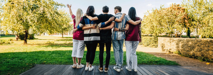 Eine Gruppe von jungen Männern und Frauen in Arbeitskleidung stehen auf einem Weg. 