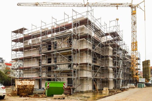 Ein großer Kran steht über dem Bau, der von einem großen Baugerüst umgeben ist