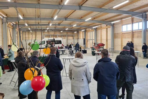 Mehrere Personen mit vielen Party-Luftballons stehen in der neuen großen Halle