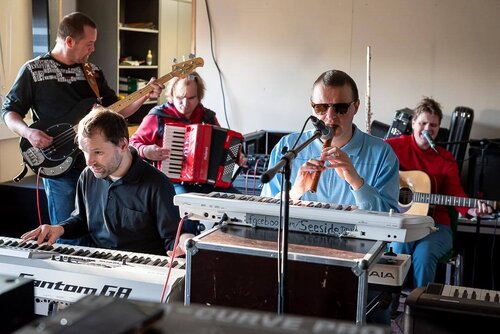 Die Band sitzt im Probenraum an ihren Instrumenten