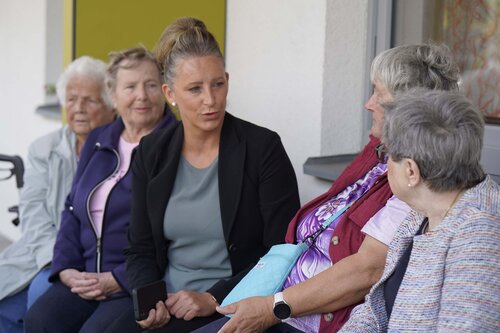 Eine Pflegefachkraft sitzt mit vier Seniorinnen auf einem Hausflur im Betreuten Wohnen in der Soldmannstraße in Greifswald