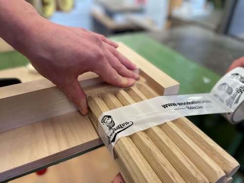 Gefertigte Holzstäbe werden mit einem Warenband zusammen verpackt 