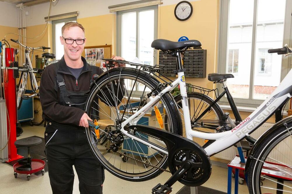 Ein Mitarbeiter repariert das Hinterrad eines Fahrrades