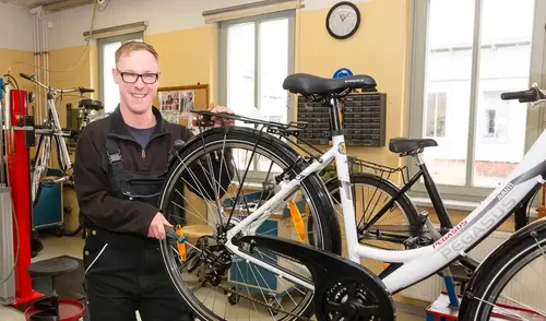 Ein Mitarbeiter repariert das Hinterrad eines Fahrrades