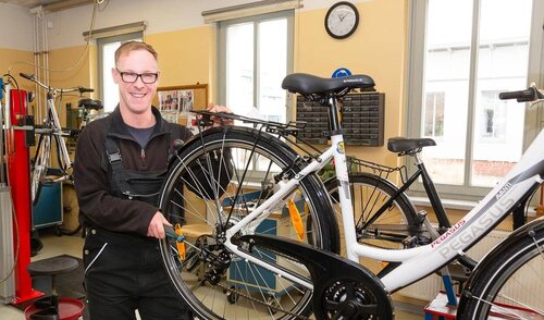 Reperatur eines Fahrrads in der Fahrradwerkstatt Ein Mitarbeiter repariert das Hinterrad eines Fahrrades