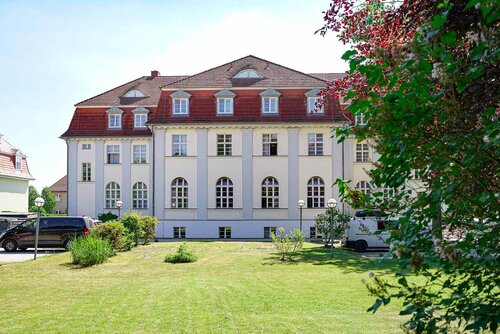 Gebäuderückseite des Annastifts Jarmen, davor eine Rasenfläche und ein Baum