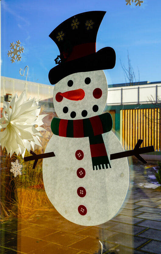 Ein gebastelter Schneemann schmückt ein Fenster