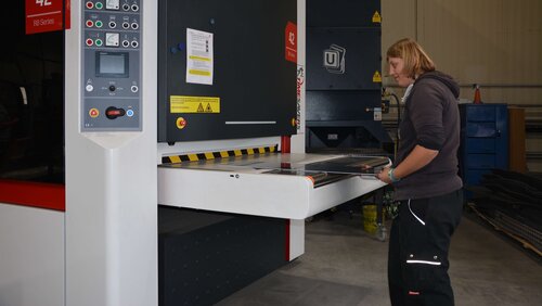 Eine junge Frau bedient Metallverarbeitungsmaschine Frau an Maschine