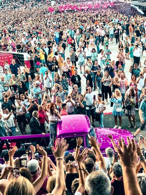 Eine große Menschenmenge und ein altes Auto feiert