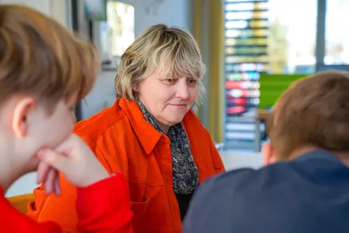 Eine Mitarbeiterin sitzt mit zwei Jugendlichen zusammen