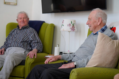 Zwei Herren sitzen in gemütlichen Sesseln in einem Raum und unterhalten sich