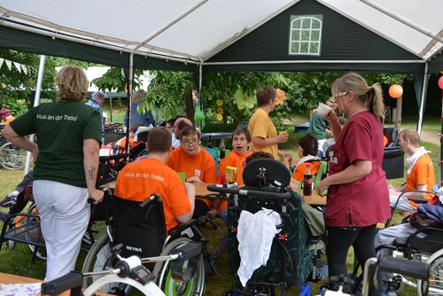 Mitarbeitende und Bewohner an einem Tisch unter einem Pavillon