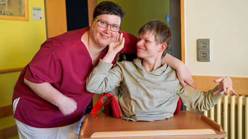 Eine Frau umarmt einen jungen Mann im Rohlstuhl