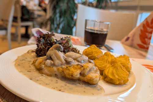 Ein Mittagsgericht mit Kroketten, Champignongs und Schnitzel auf einem Teller