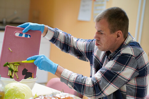 Ein Mann wischt Gemüse von einem Schneidbrett mit einem Messer