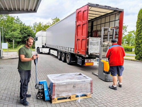 Mitarbeiter transportieren eine Euro-Palette in einen LkW.