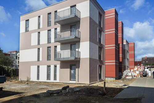 Ein Gebäude mit drei Stockwerken und Balkonen an der Seite