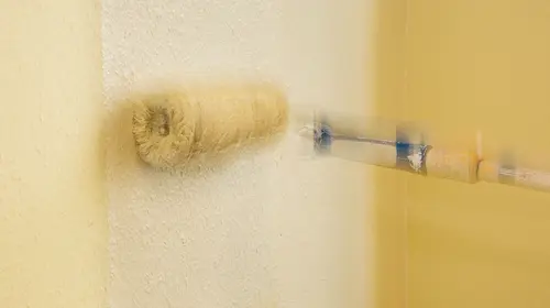 Eine Farbwalze streicht eine Wand mit Farbe