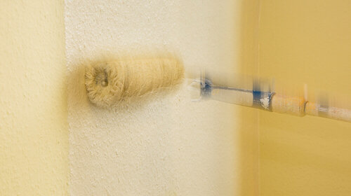Eine Farbwalze in Aktion Eine Farbwalze streicht eine Wand mit Farbe