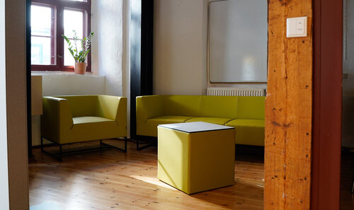 Eine Couch, Hocker und Altbau-Fussboden