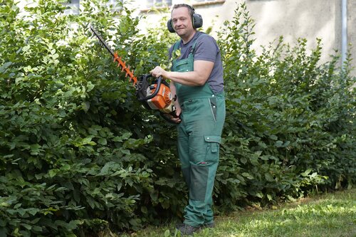 Ein Mann schneidet eine Hecke mit einem elektronischen Gerät