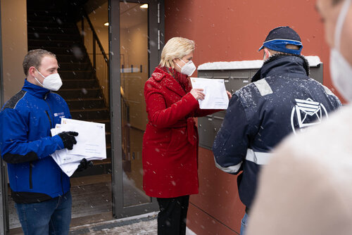 Frau Schwesig steht vor der Briefkastenanlage und wirft Umschläge hinein