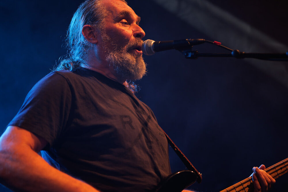 Michael Turban steht an einem Mikrofon mit einer Gitarre und singt