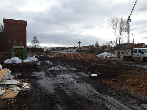 Eine erdige Fläche mit Pfützen und einigem Müll am Rand