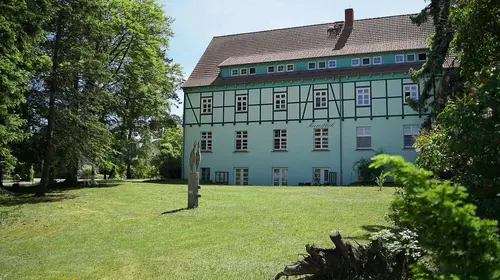 Eine große alte Fachwerkvilla vor Rasen und Bäumen