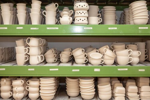 Ein Regal mit aufeinander gestapelten Keramikprodukten Regale voller Töpferware