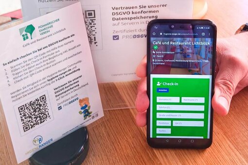 Ein Smartphone mit dem Check-In Formular des Hygiene-Rangers und ein erklärender Aufsteller