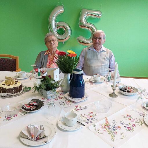 Zwei ältere Menschen sitzen an einem festlich gedeckten Tisch