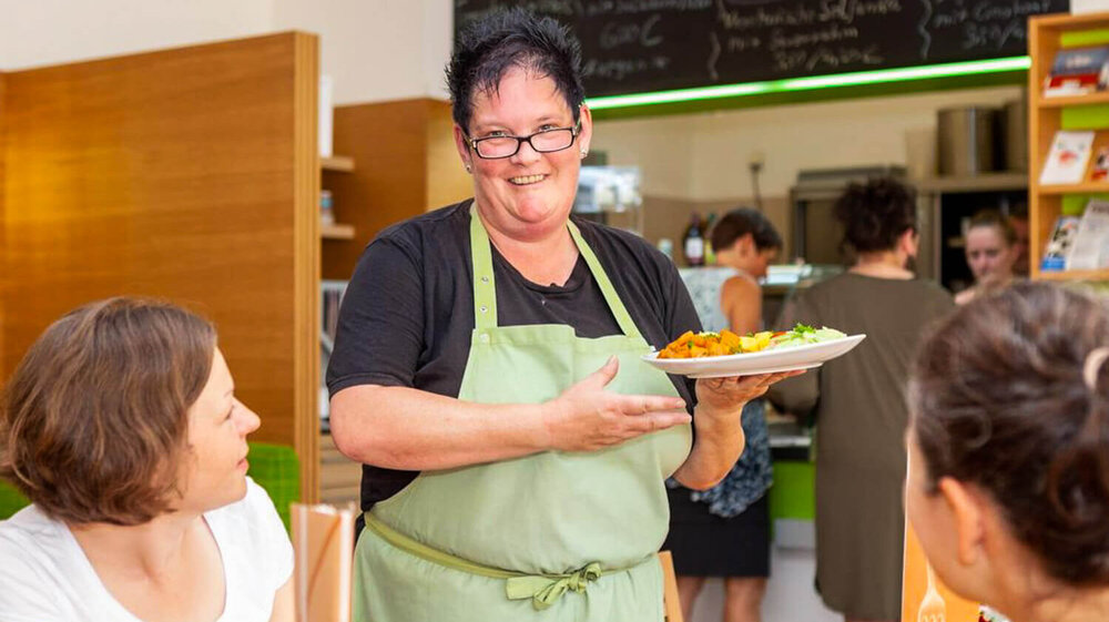Eine Frau bedient im Bistro Alte Sternwarte in Greifswald Gäste am Tisch