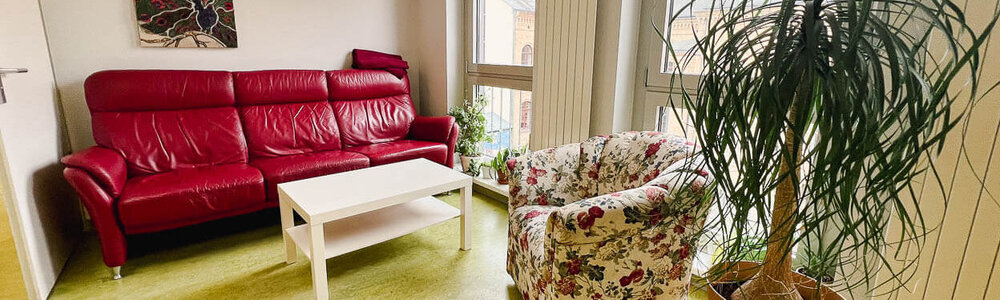 Eine Sitzecke mit Sofa, Couchtisch und Sessel und einer Pflanze in der Tagesgruppe Steg Greifswald