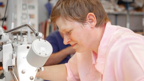 Eine Frau arbeitet an einer Maschine Frau an Nähmaschine