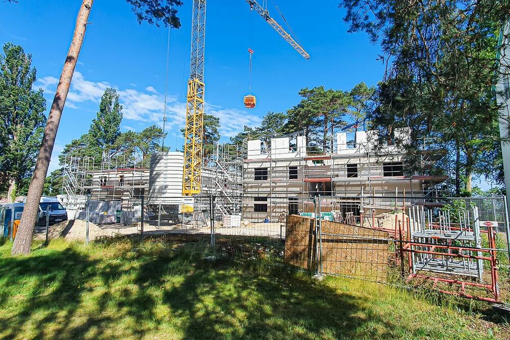 Ein Bauzaun um die Baustelle, auf bereits das 2. OG gemauert wird