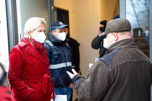 Manuela Schwesig spricht mt einem älteren Herrn vor den Briefkästen des Hauses