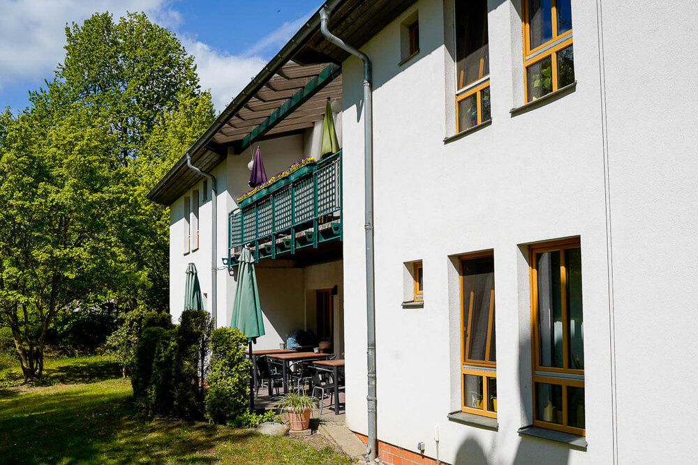 Ein Wohngebäude mit zwei Stockwerken, Balkon und Terrasse im Erdgeschoss