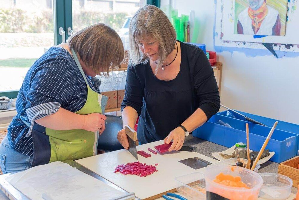 Zwei Frauen arbeiten an einem Häufchen mit Wachsstücken