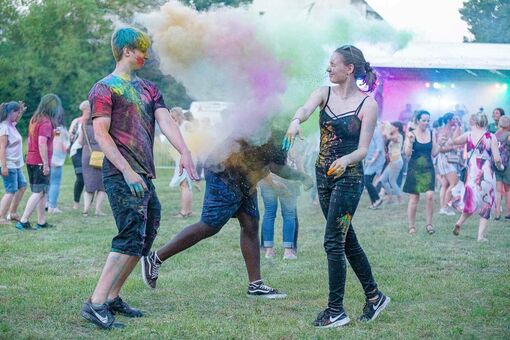 Ein junger Mann und eine junge Frau bewerfen sich gegenseitig mit Farbpulver