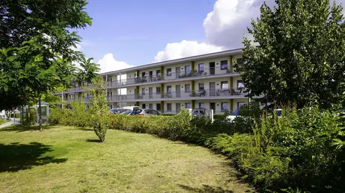 Eine Parkanlage vor einem dreistöckigen Gebäude in Greifswald