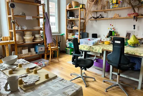 Ein Raum mit Regalen, Stühlen und Tischen mit Töpferutensilien in der Begegnungsstätte Steg