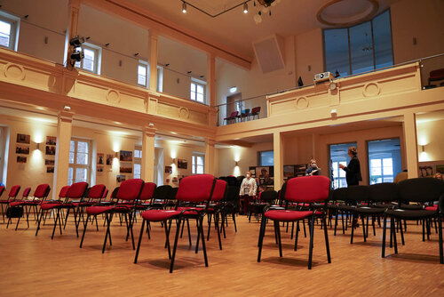 Ein großer Saal wie in einem Theater, in dem viele einzelne Stühle stehen