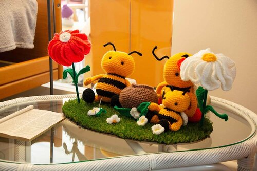Gehäkelte Bienen sitzen auf einer ebenfalls gehäkelten Grünfläche mit gehäkelten Blumen